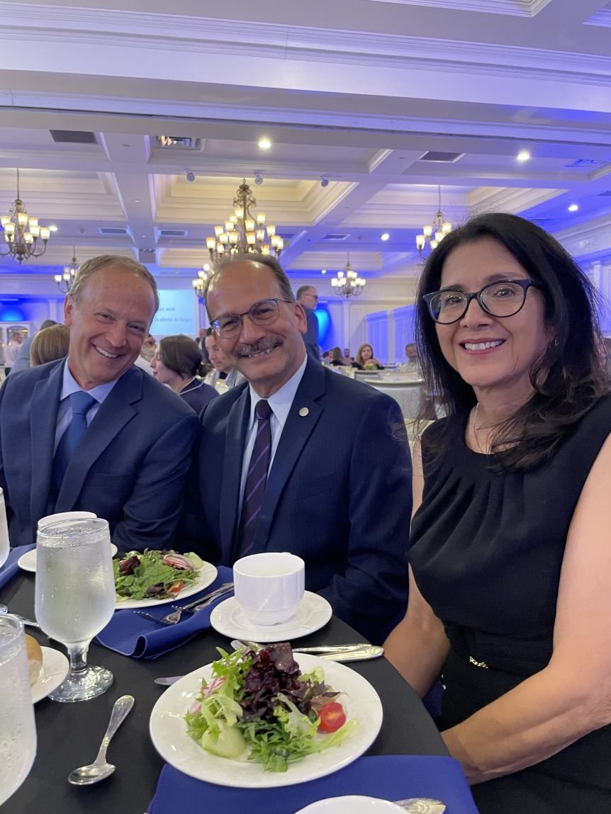 Three people smile for a photo, seated at a dinner table at the MDA event. Left to right: Andy Berglund, Havidán Rodríguez, Rosy Rodríguez. 
