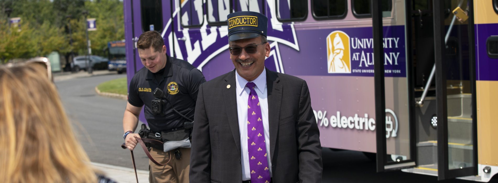 President Havidán in a Conductor hat in front of the new UAlbany trolley 