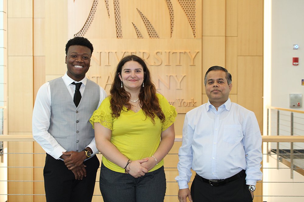 UAlbany Senior Eugene Marco, left, and Md. Aynul Bari, right, stand with another NSF student in front of a UAlbany Minerva in the ETEC building.