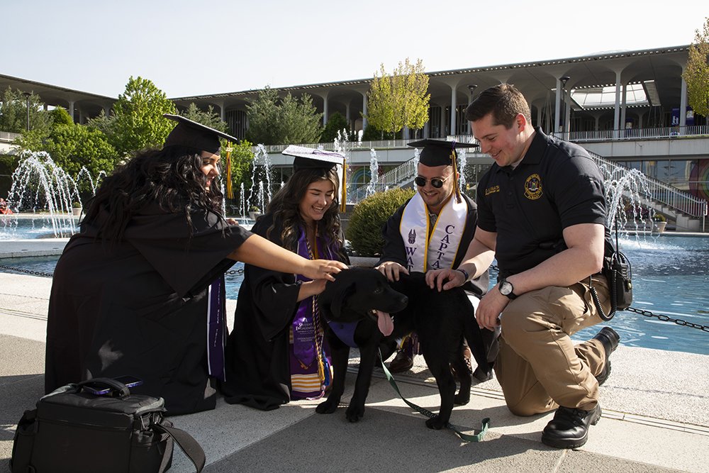 Officer Faath and Roxy meet with students preparing to graduate in May 2023 on the Campus Podium.