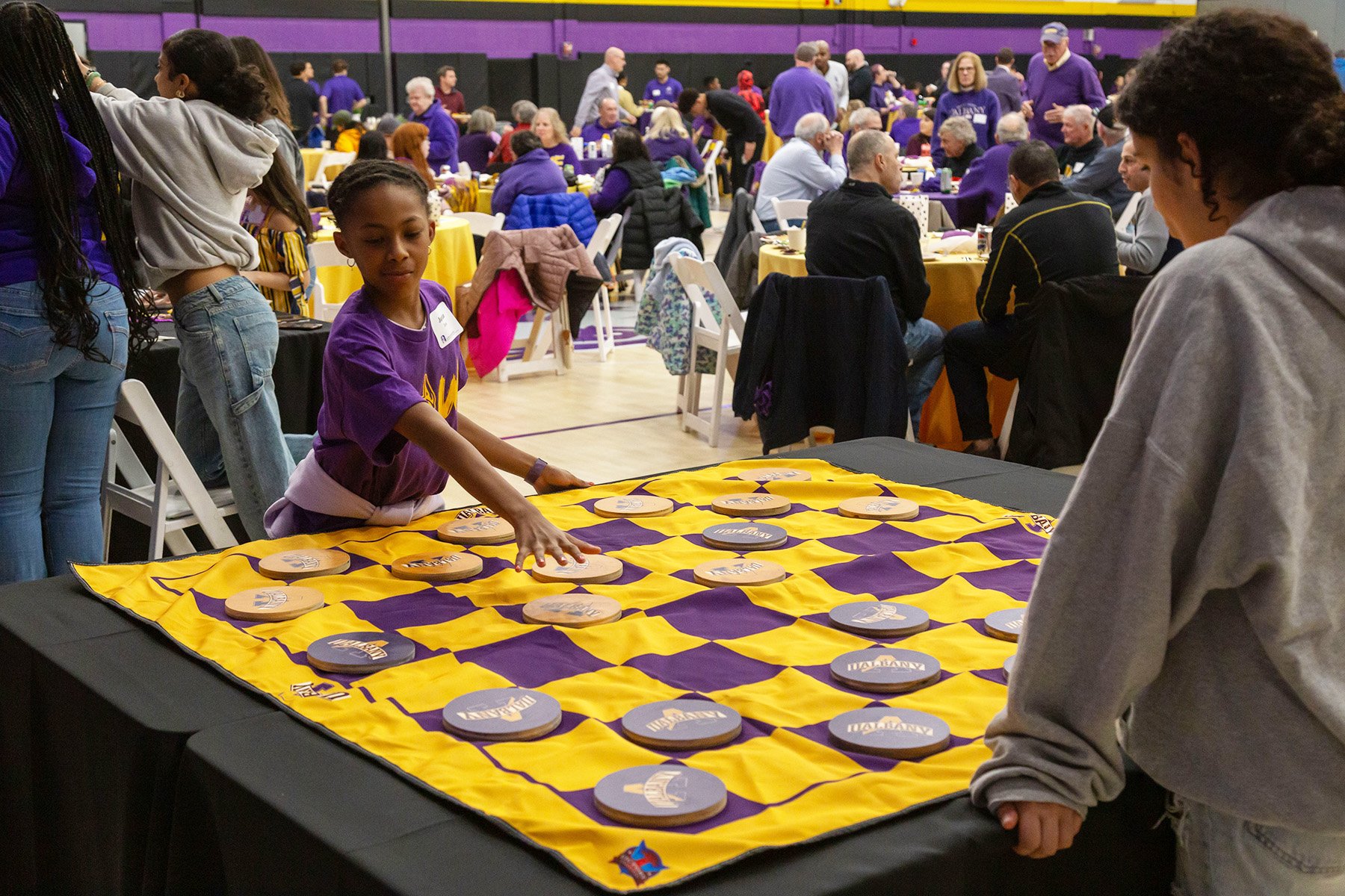Kids play a giant game of checkers during the 2024 Ferocious Feast at the PE Gym.