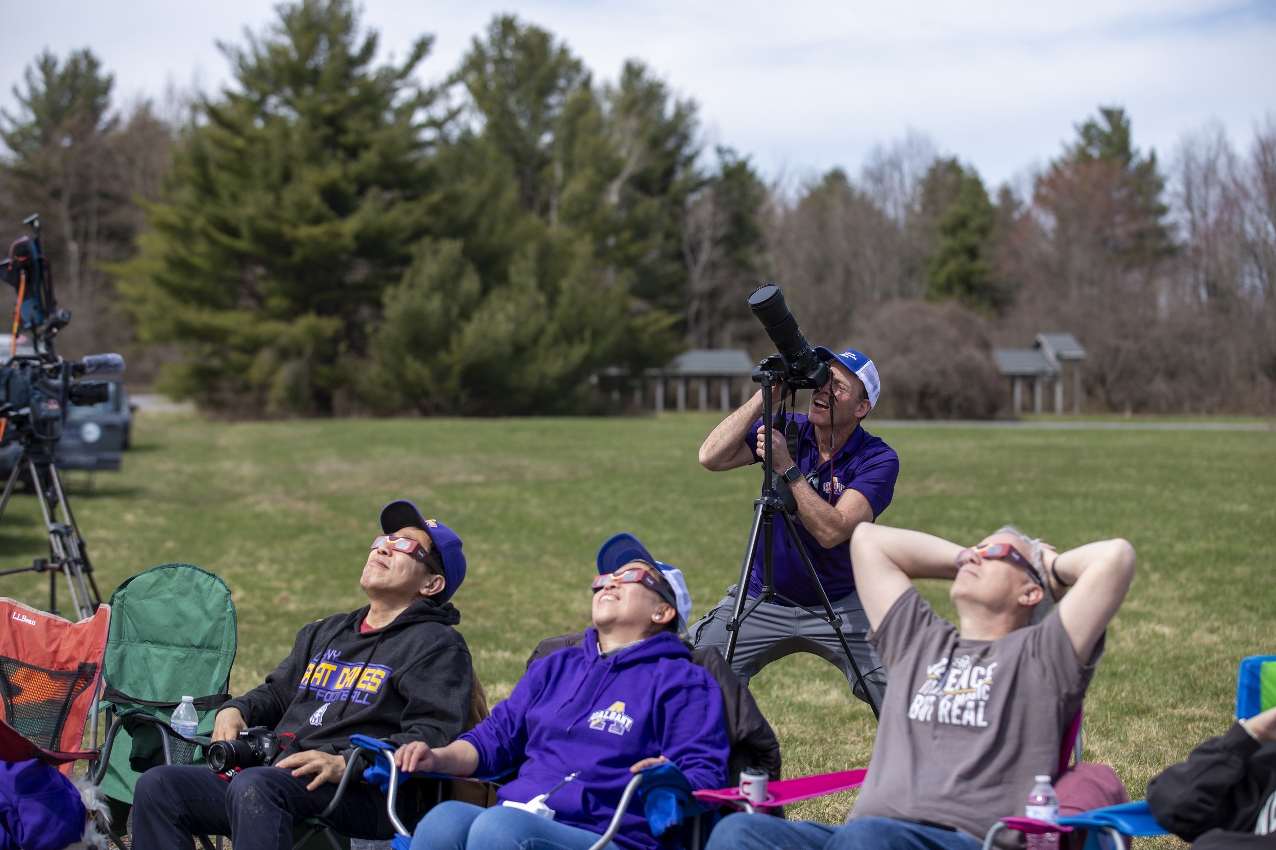 UAlbany students and faculty use solar eclipse glasses to look up at the sun.
