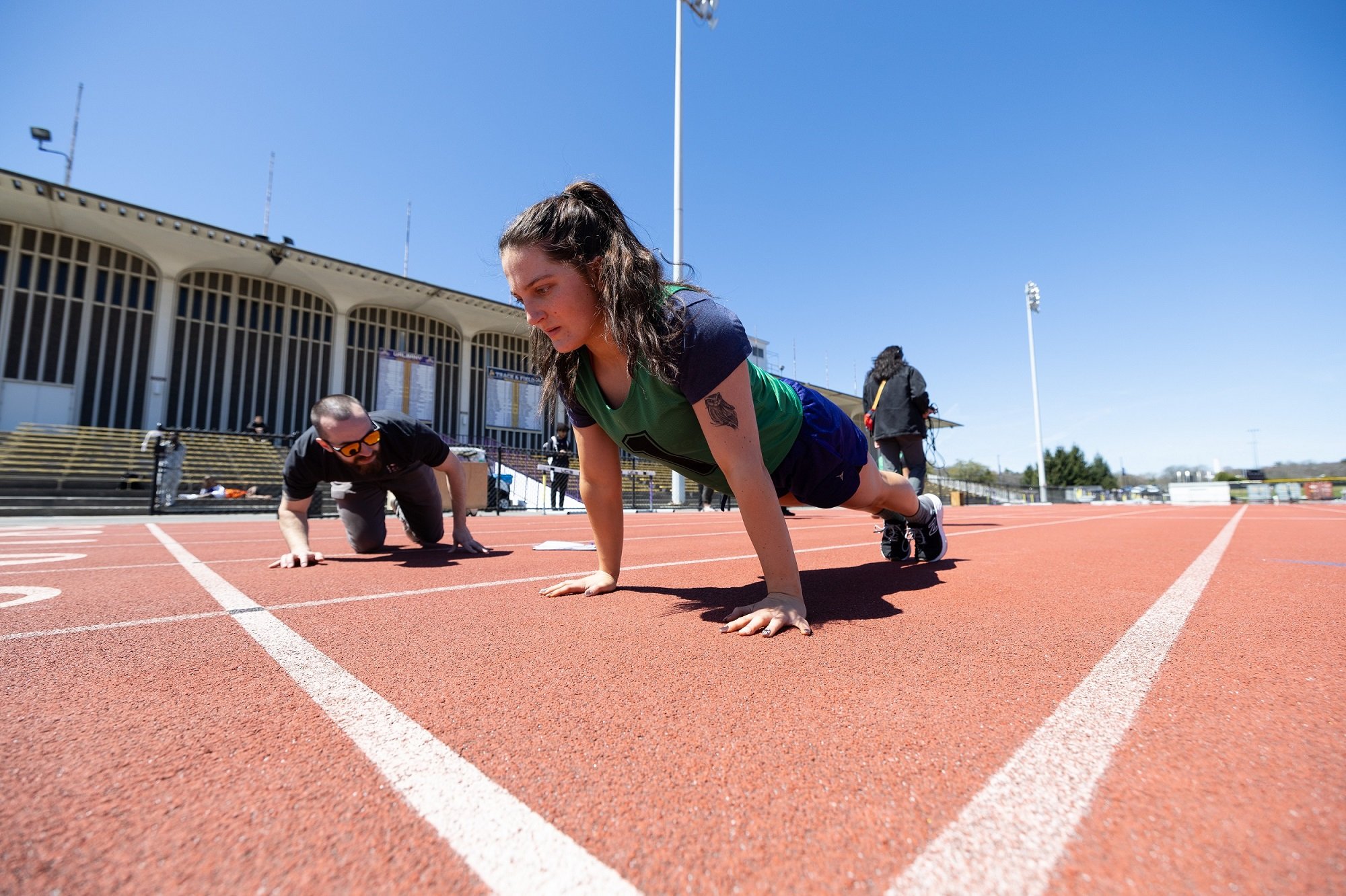 A student does a push up next to FBI personnel  during the physical fitness test at UAlbany.