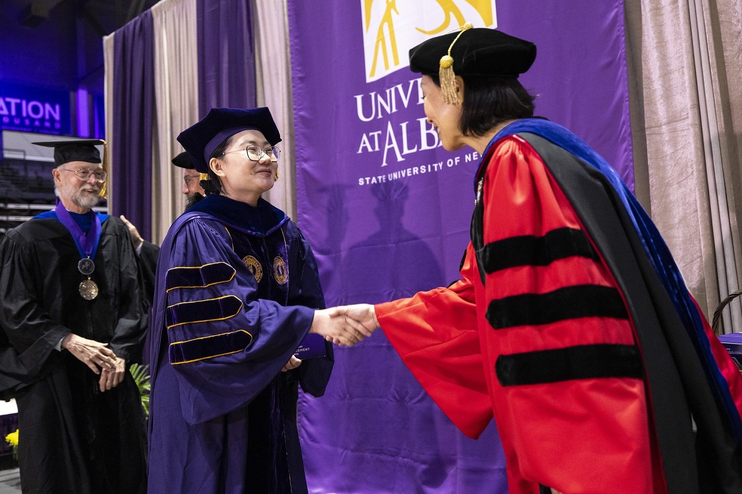A UAlbany PhD graduate shakes hands with Provost Carol Kim as she crosses the stage.