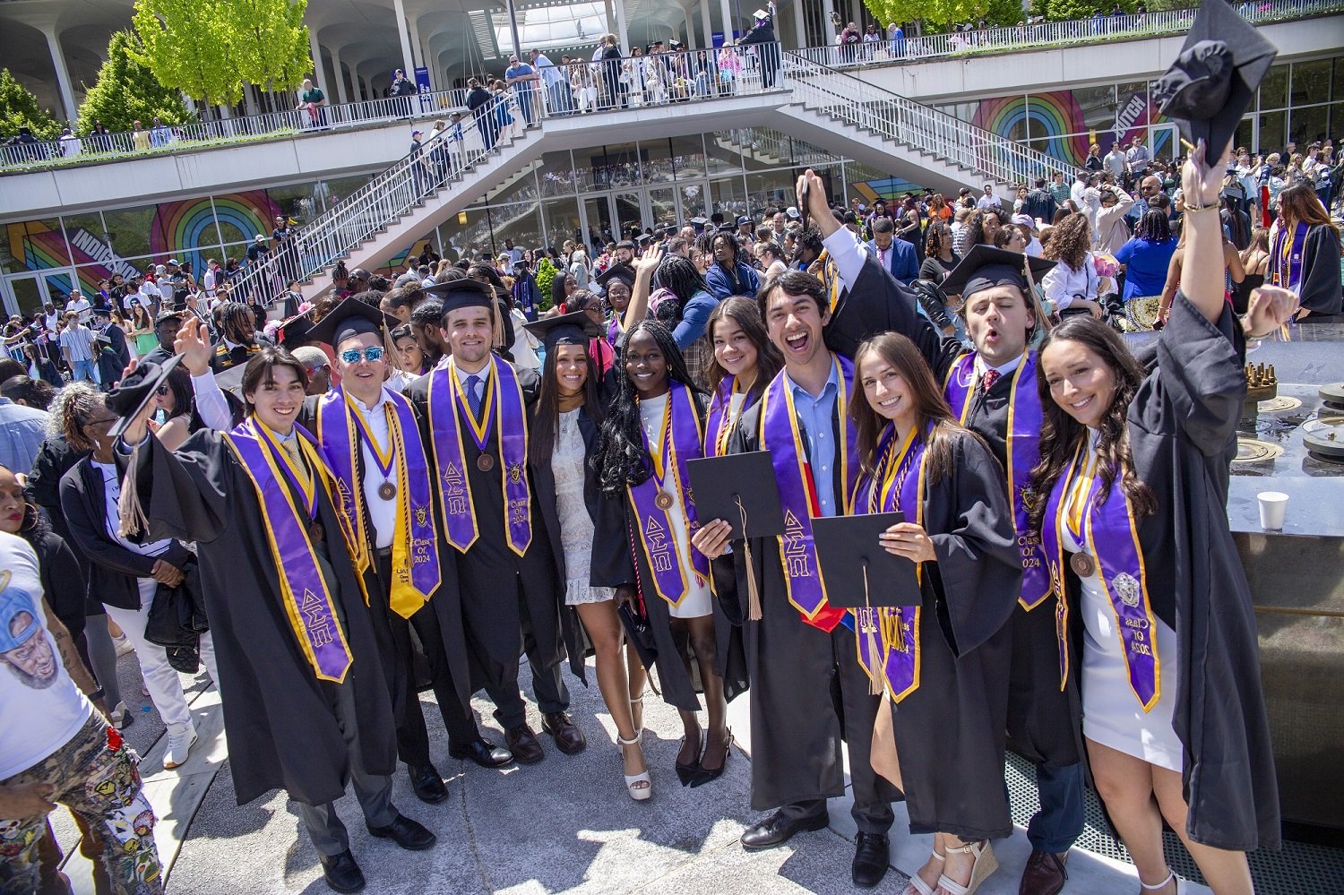 UAlbany graduates stand on a platform at the main fountain after the 2024 undergraduate commencement ceremony.