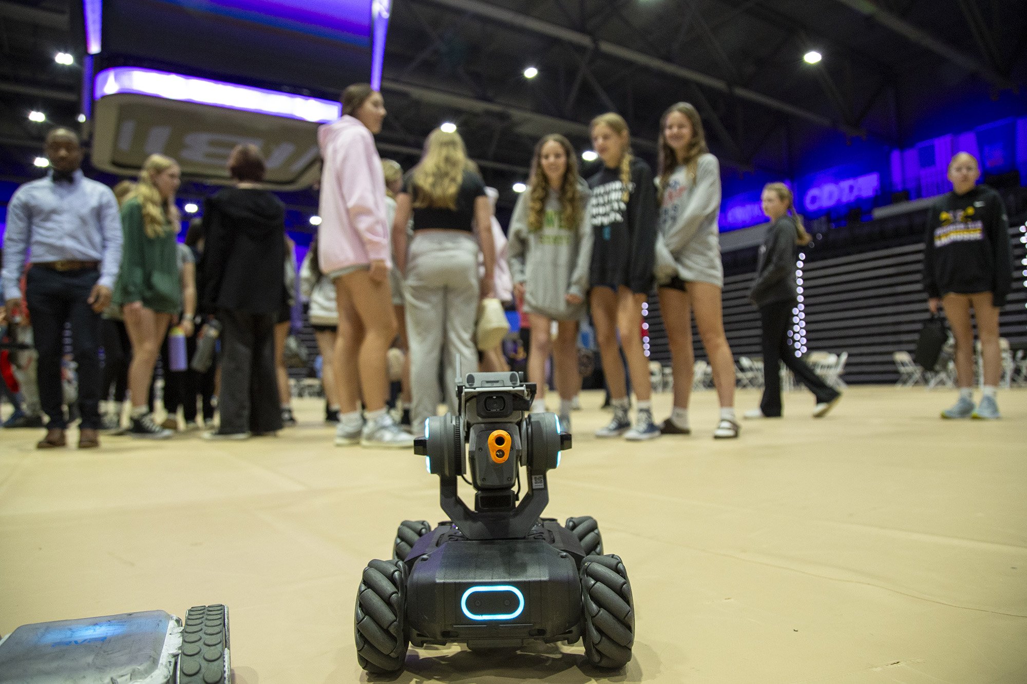 A robot moves towards a group of girls in the background at Showcase Day at Broadview Center.