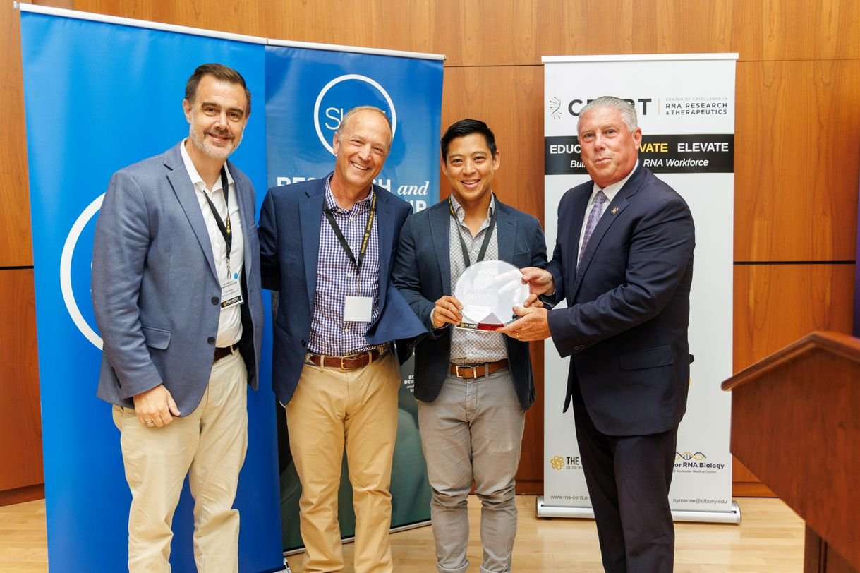 Four men pose together for a group portrait.