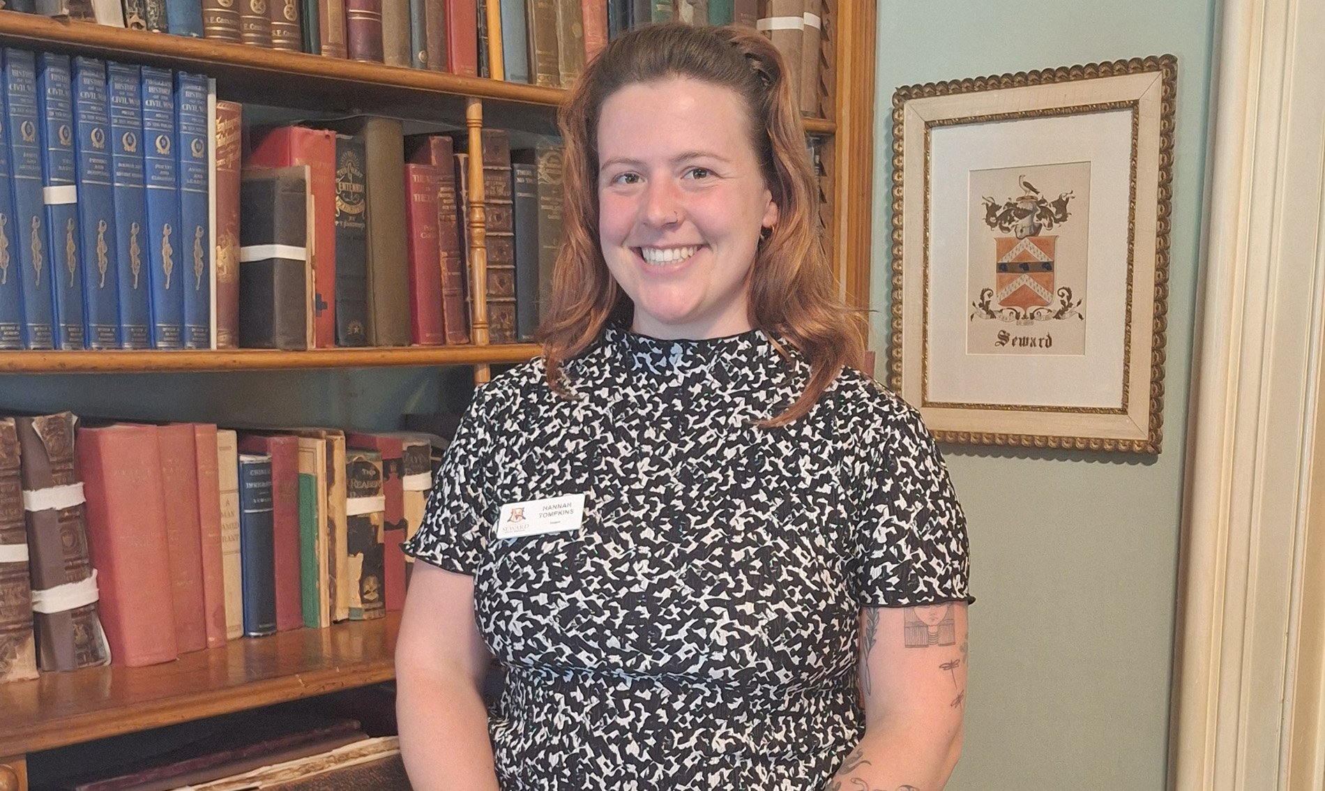 Hannah Tompkins stands in front of a book shelf. 