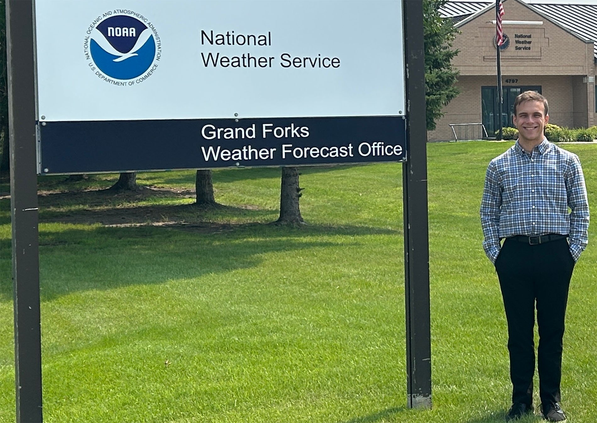 Daniel Harkin stands in front of the NWS Grand Forks sign.