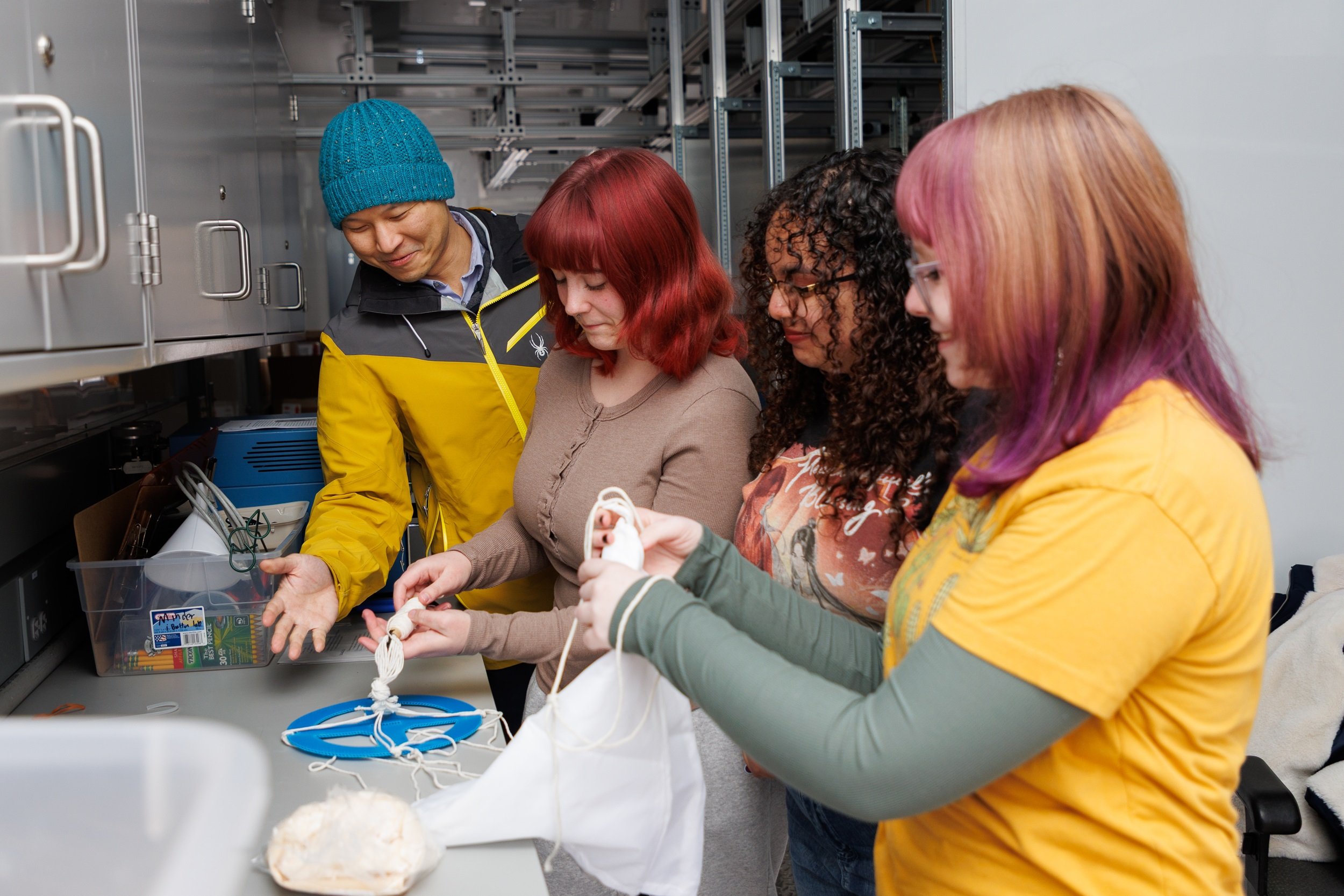 Professor Brian Tang helps students collect weather balloon instrumentation and prepare it for launch.