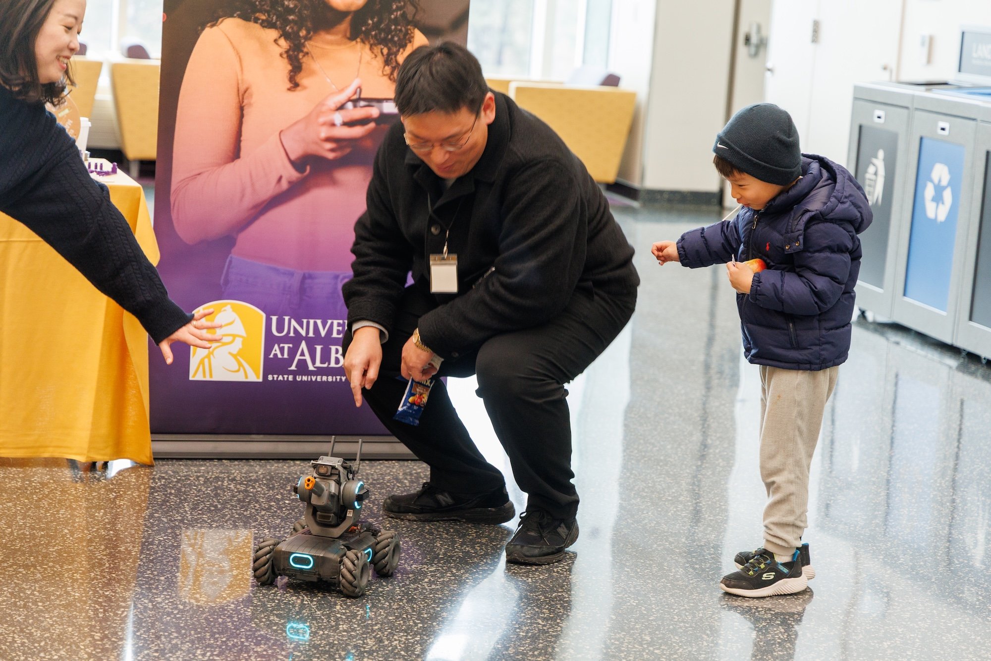 A man and young boy play with a robotic vehicle