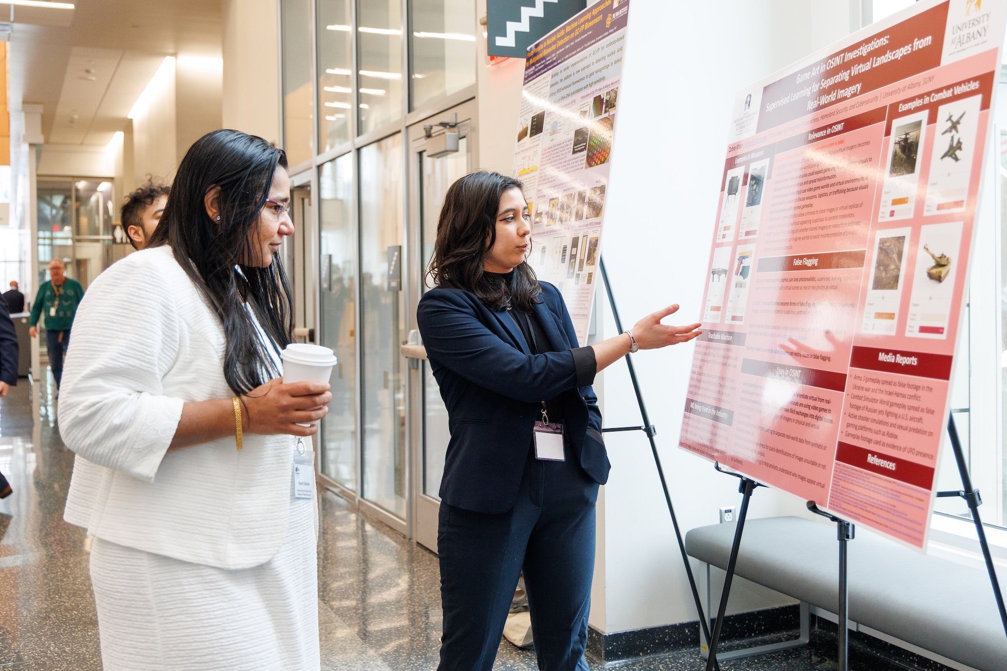 A woman gestures toward a poster as she speaks to a woman nearby