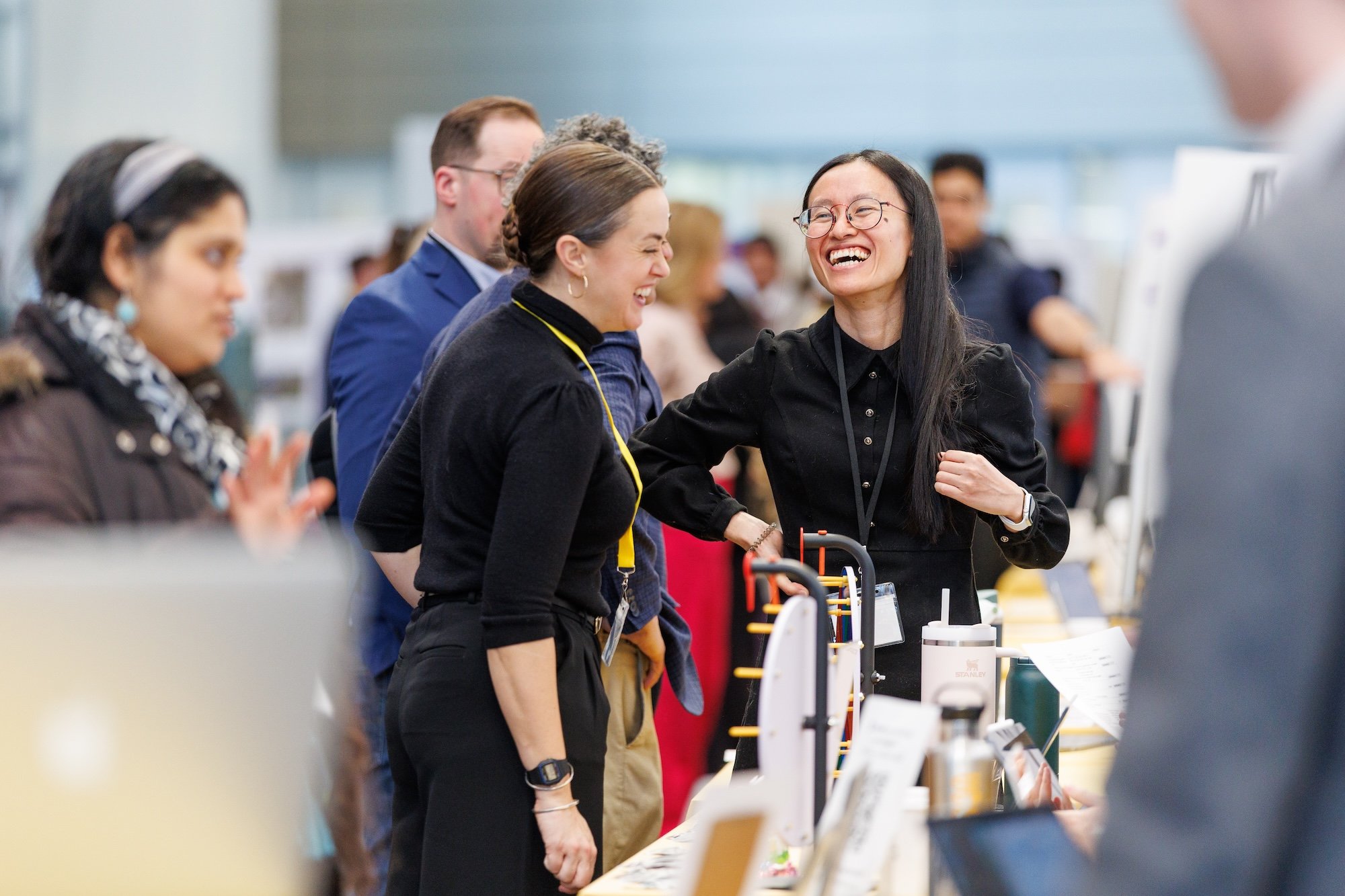 Women gathered around a table smile and laugh