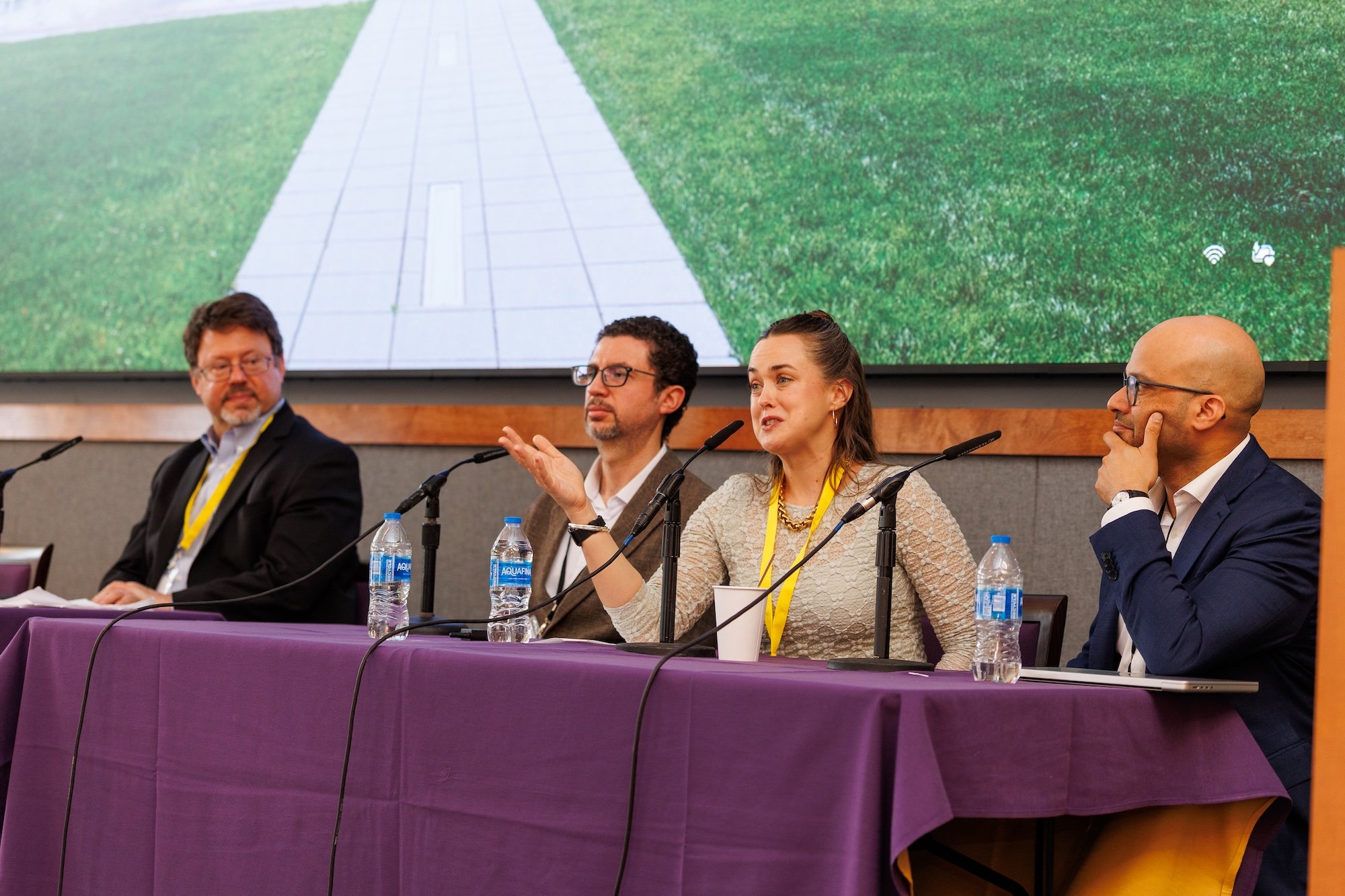 A woman speaks into a microphone as part of a panel discussion