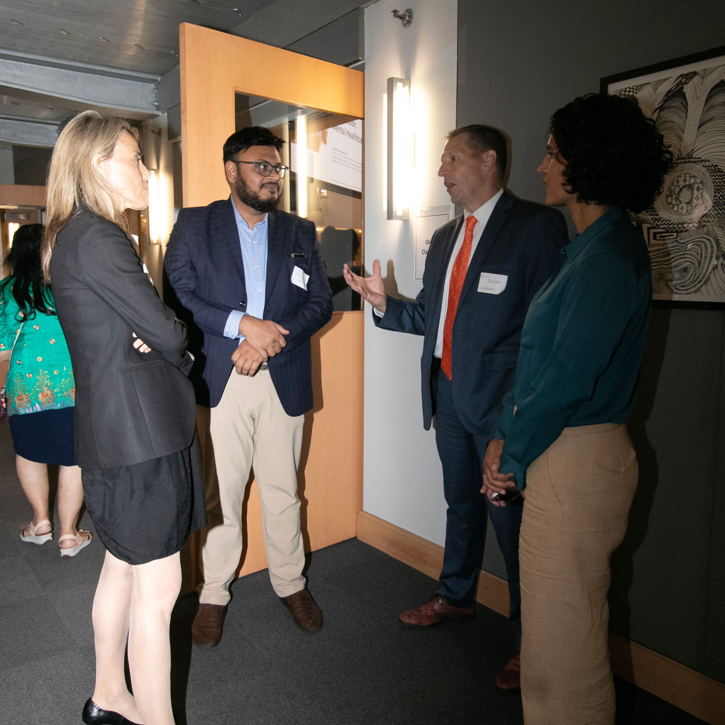 Four individuals talking with one another at the 2nd Annual Summit for the Global Center in AI Mental Health at the Suny Global Center in NYC.