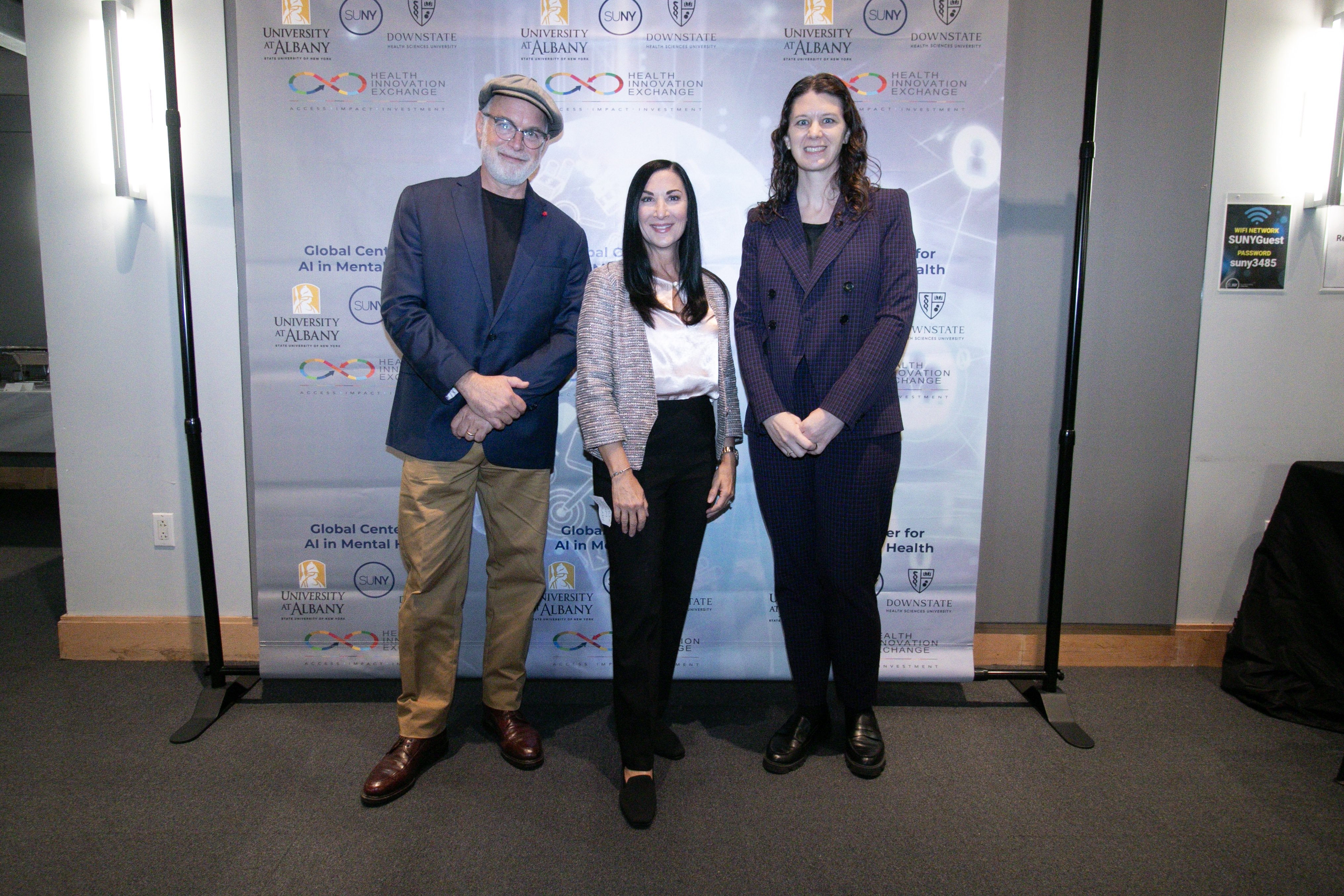 Three individuals smiling for photo at the 2nd Annual Summit for the Global Center in AI Mental Health at the Suny Global Center in NYC.