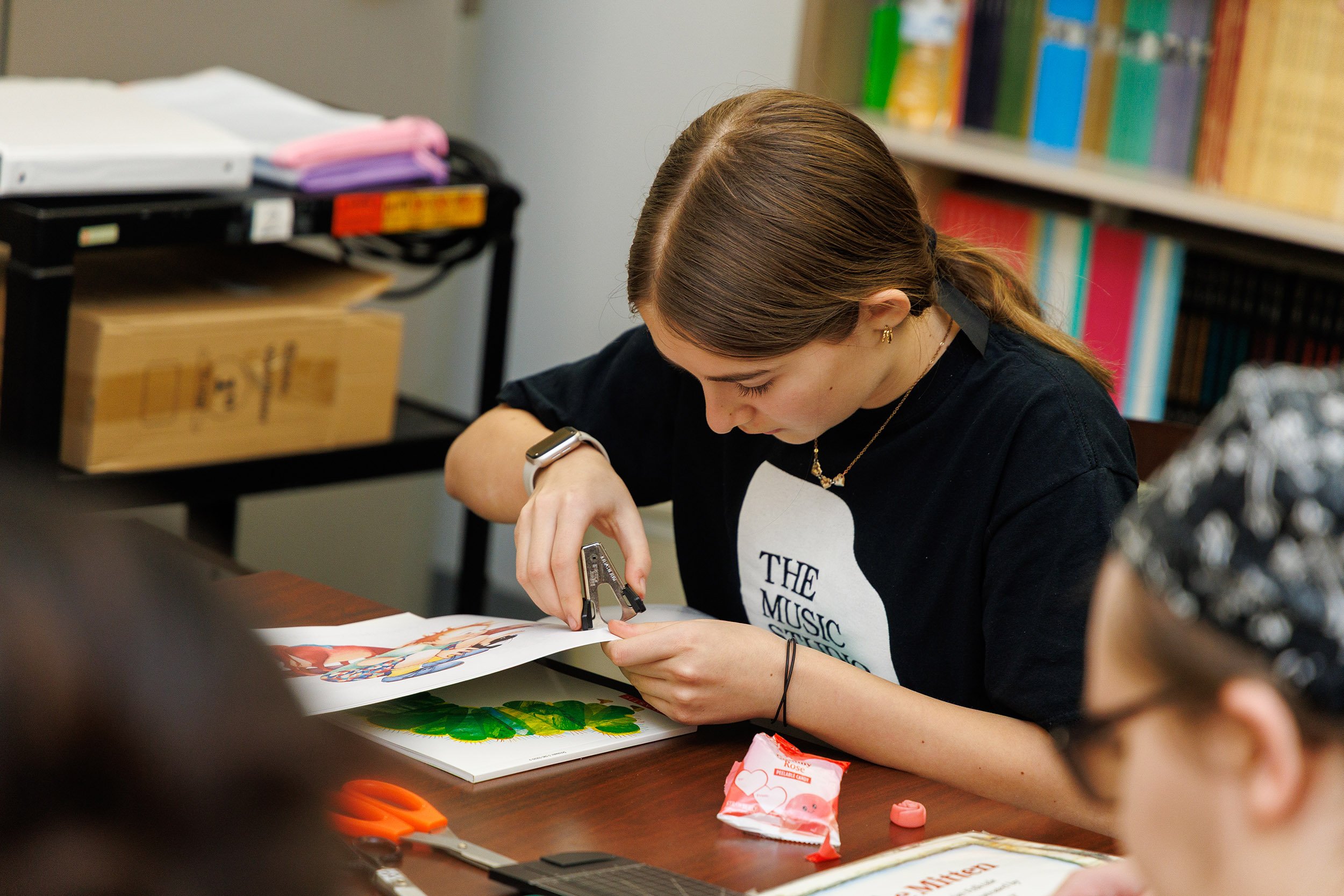 A student prepares materials for an adapted book during a class workshop.