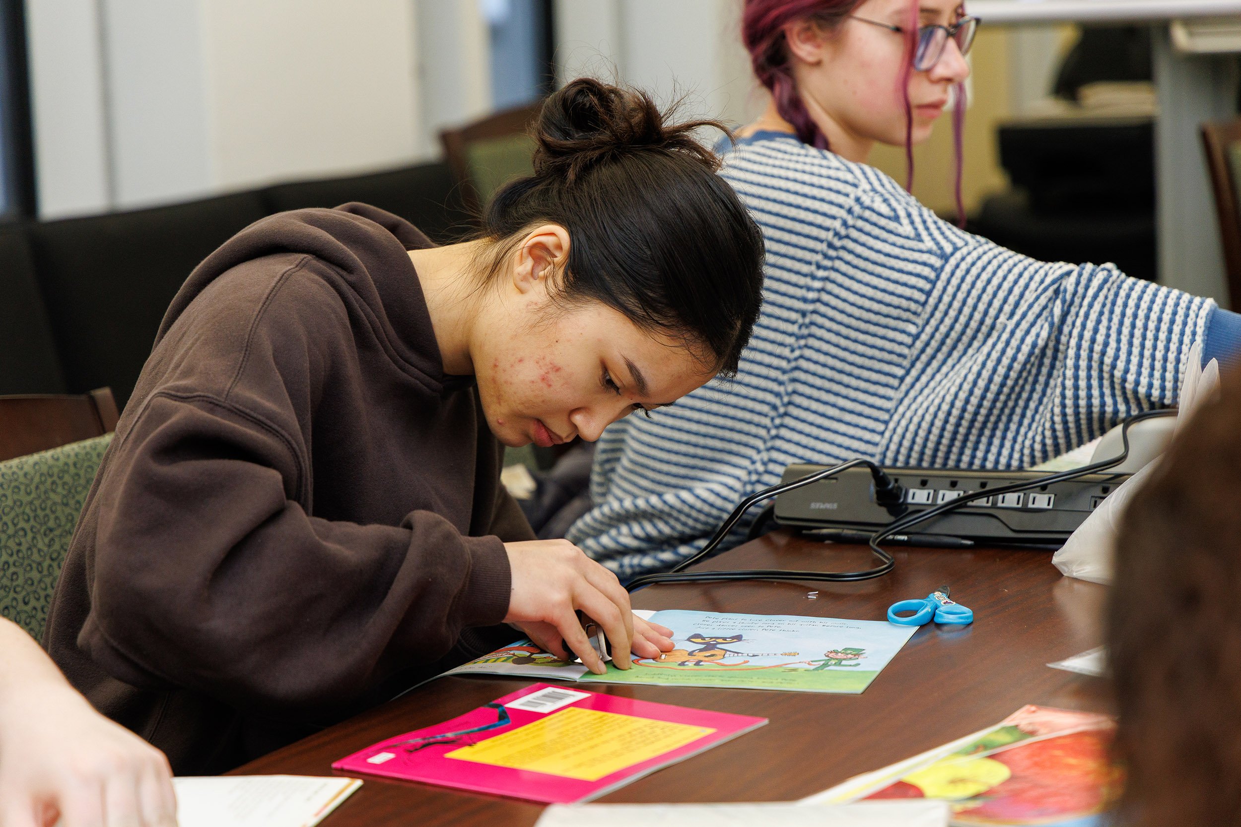 A student prepares materials for an adapted book during a class workshop.