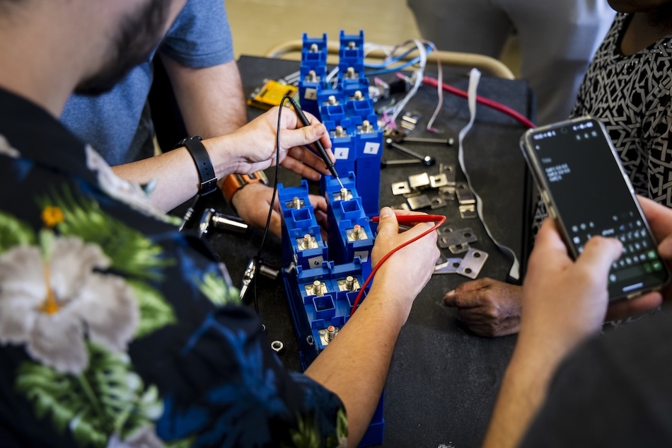 People in safety glasses gather in a laboratory for a training on energy storage technologies