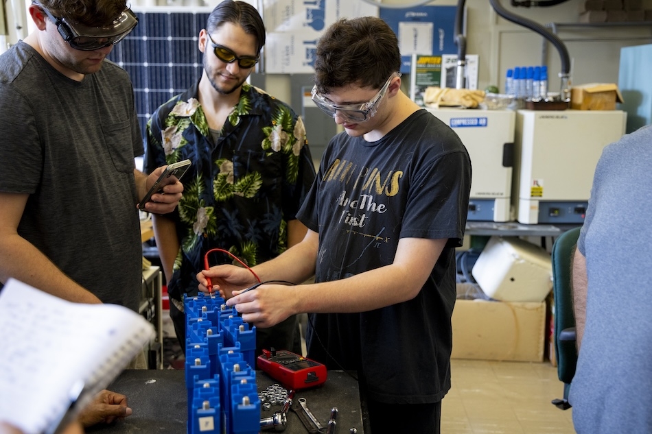 People in safety glasses gather in a laboratory for a training on energy storage technologies