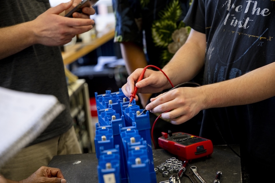 People in safety glasses gather in a laboratory for a training on energy storage technologies