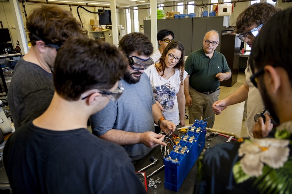 People in safety glasses gather in a laboratory for a training on energy storage technologies