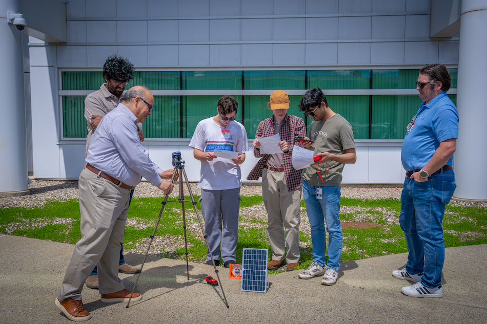 People gather around a solar panel for a workshop on energy storage technologies