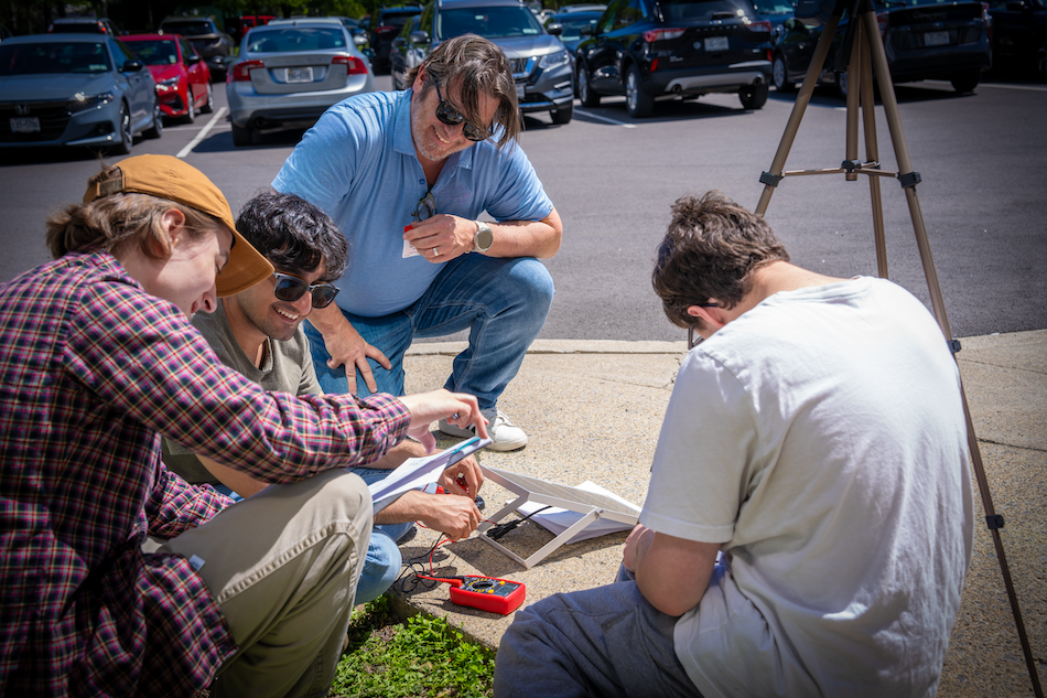 People gather around a solar panel for a workshop on energy storage technologies
