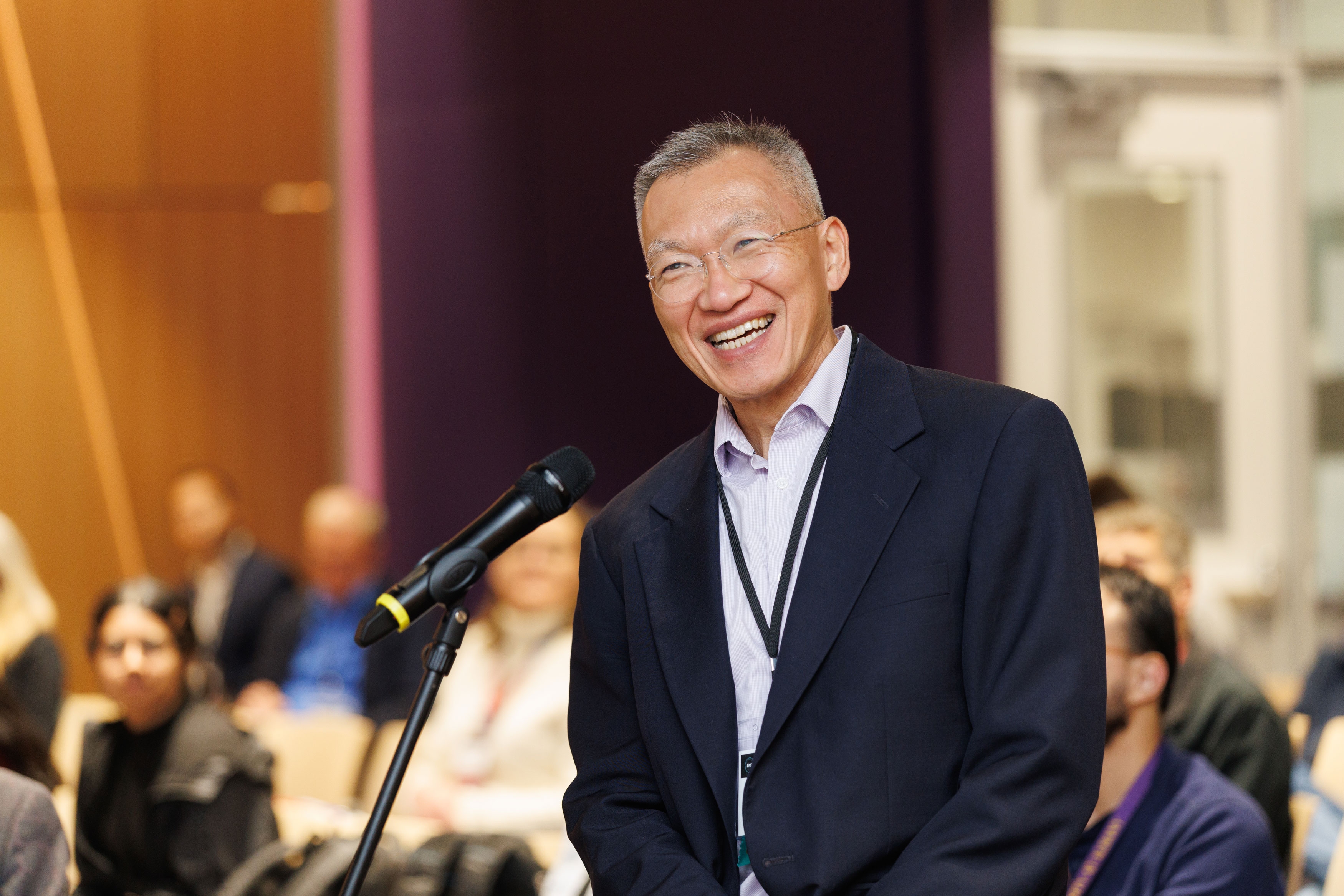 An attendee laughs while standing in front of the microphone that audience members can use to ask presenters questions at R&E Week 2025.