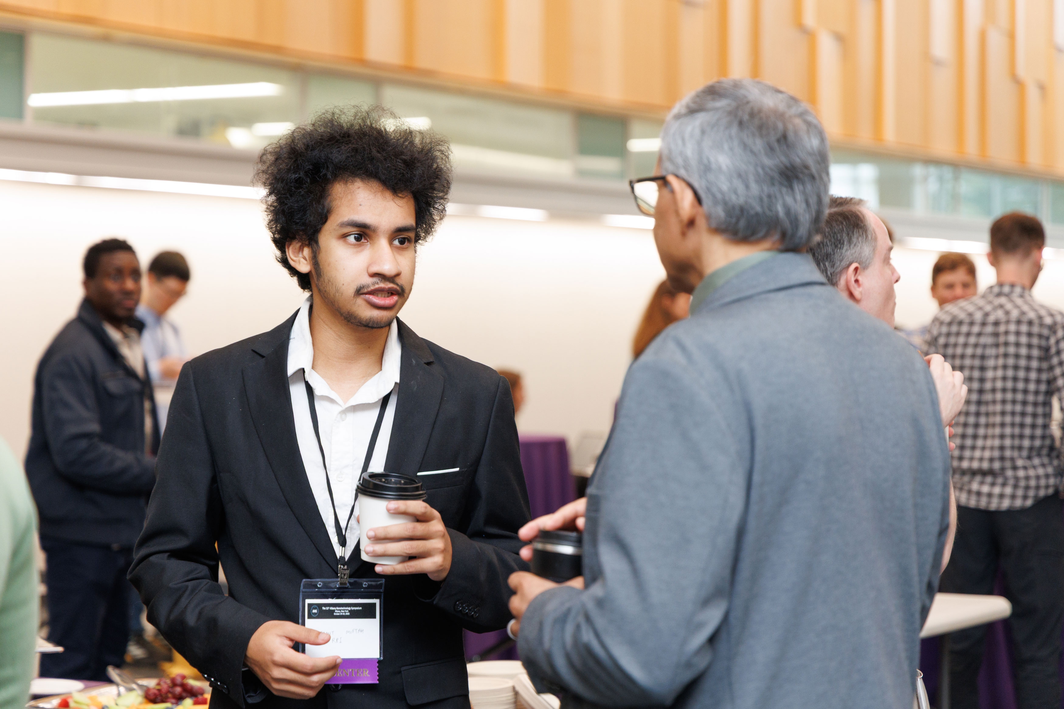 Two attendees chat and sip coffee at a networking reception during R&E Week 2025.