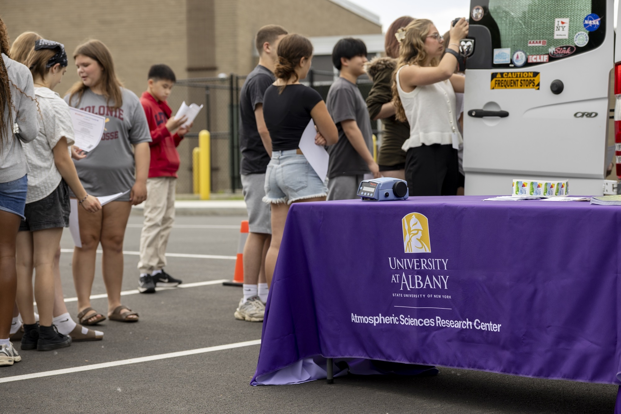 A tablecloth with UAlbany branding sits in front of ASRC's mobile lab.