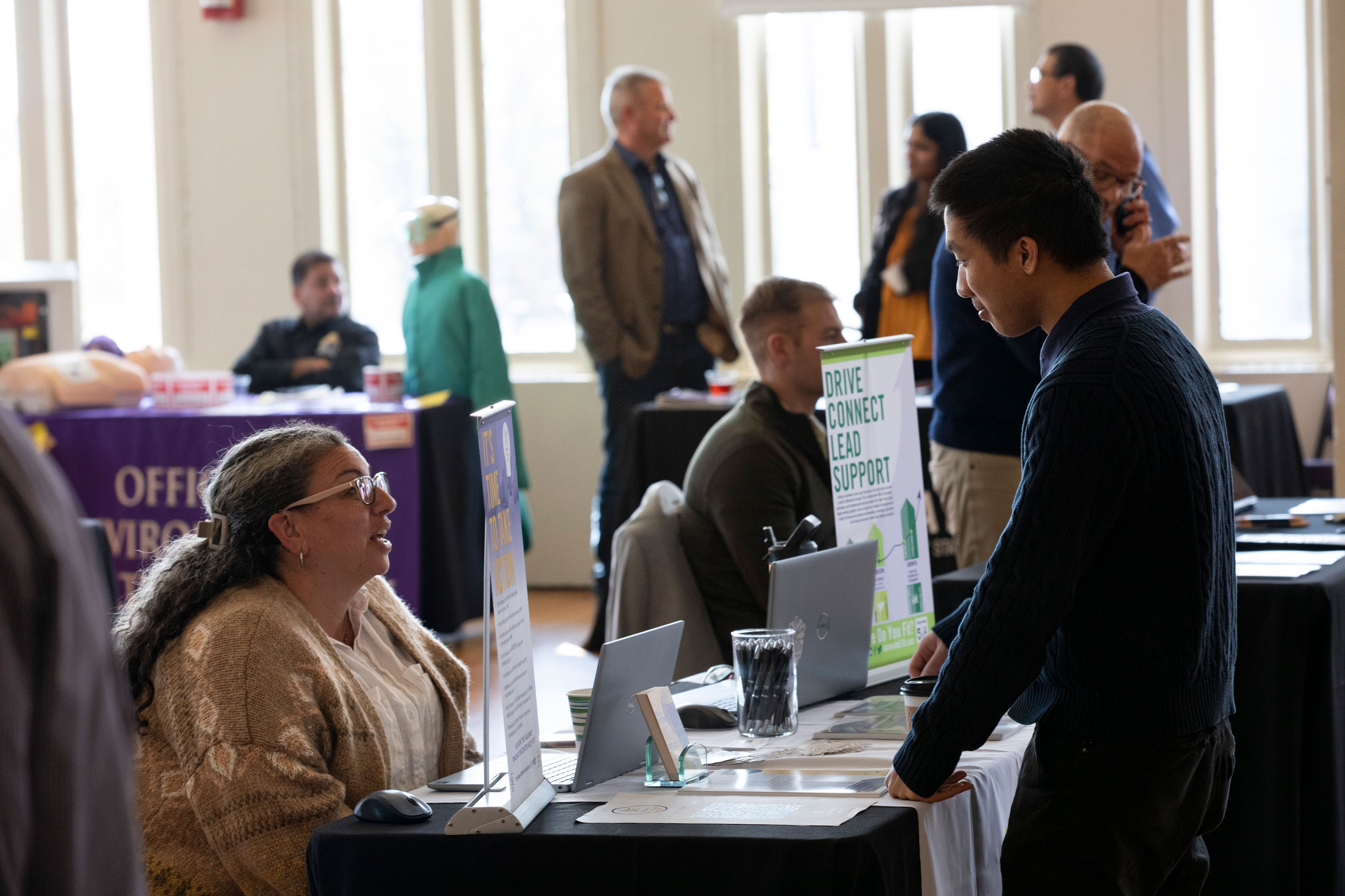 An R&E Week 2023 attendee stops to speak with a University employee staffing a table with information about entrepreneurship.