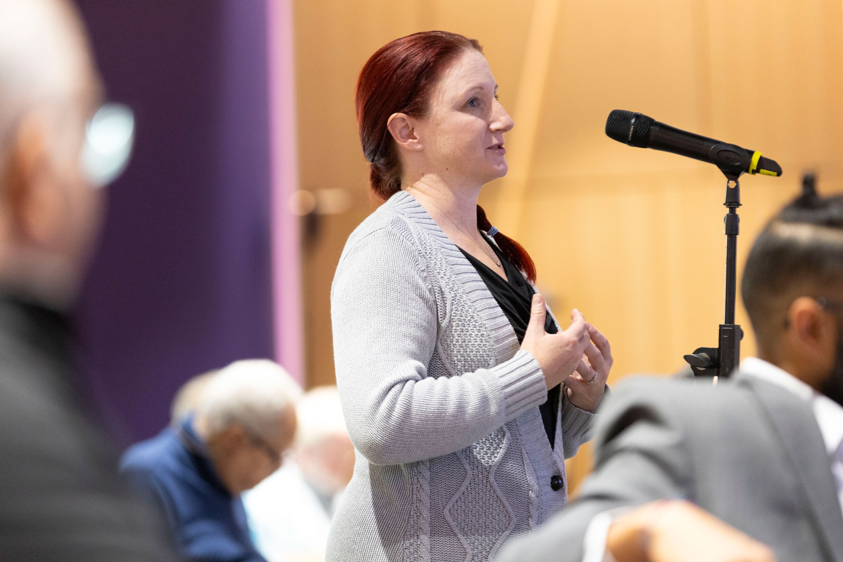 An R&E Week 2024 attendee stands at a microphone for audience members to ask a question during a presentation.