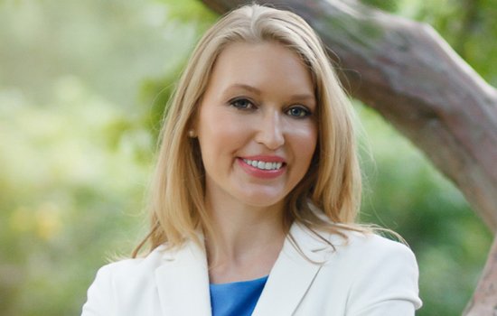 Kelly Wissman in front of a large tree branch and green foliage