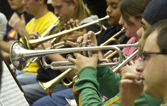 close up picture of five students playing trumpets