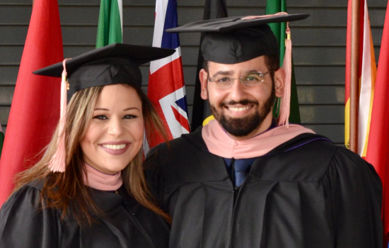 Mena and Mirna Hanna smile at the camera - they are wearing their graduation robes and hats.