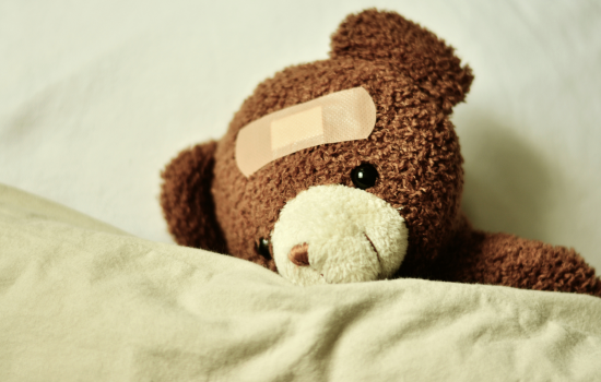 A teddy bear has a band aid on its head.