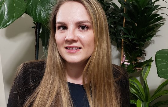 Portrait of Tatyana Tarasevich, wearing black. Plants can be seen in the background.