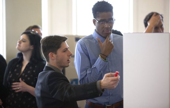Students discussing poster at CEHC Showcase event 