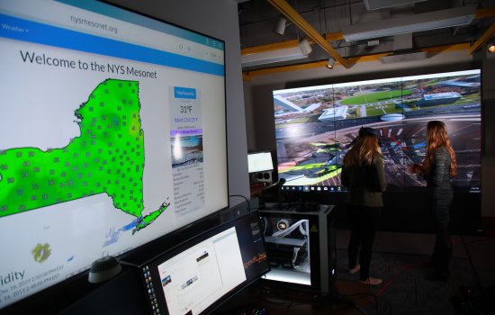 An ASRC researcher and student wear virtual reality goggles inside the xCITE lab, , a state-of-the-art data and visual analytics center.