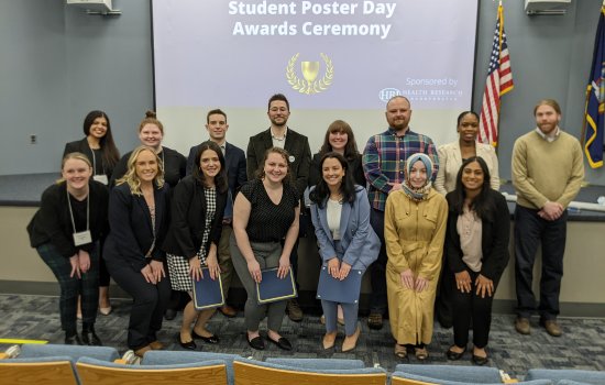 The award winners stand in front of the stage in the George Education Center auditorium, smiling.