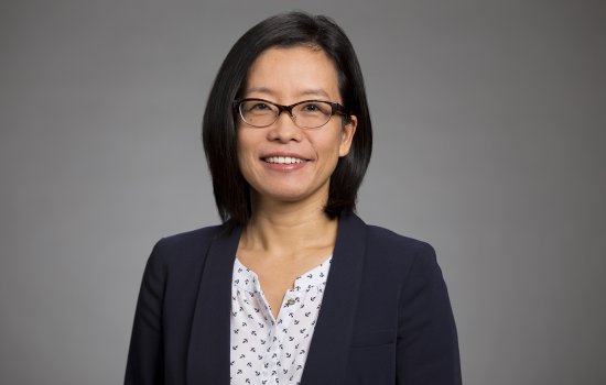 UAlbany School of Business Associate Professor Na Dai portrait - a woman wears glasses and a blue jacket.