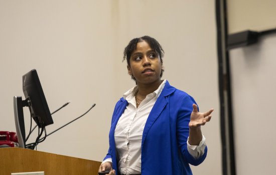 Sydney Hanson presents her research at a Lecture Center podium.