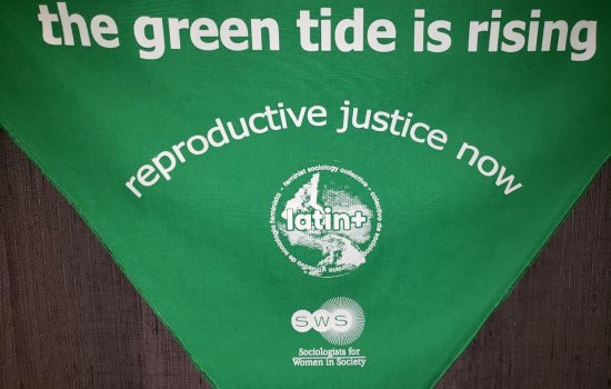 Green flag with text saying Green Tide Reproductive Justice Now on it