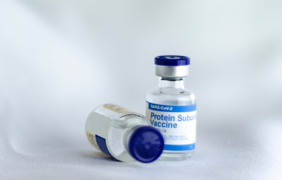 Two bottles of COVID-19 mRNA vaccines, one laying on its side.