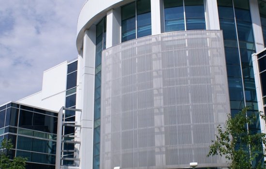 An exterior photo of a white metal and glass laboratory building that is home to the College of Nanoscale Science and Engineering.