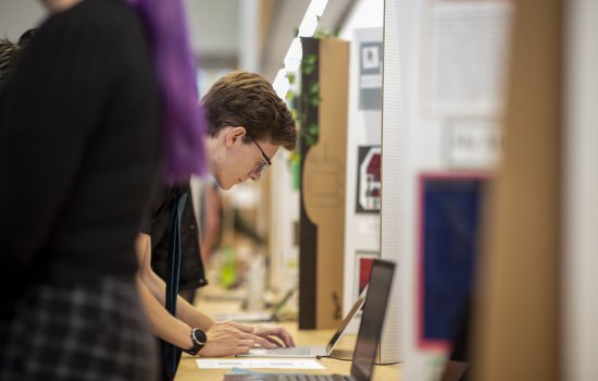 CEHC student types on computer at the Fall 2022 CEHC Showcase for presentation