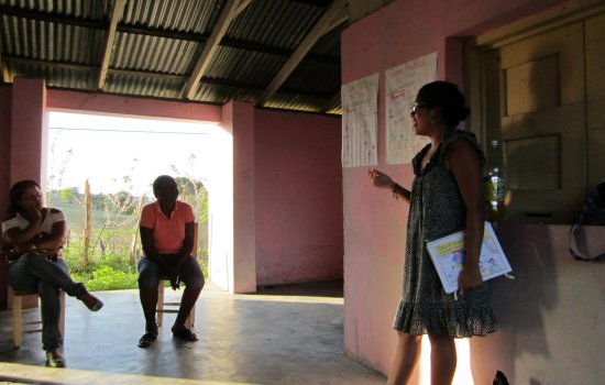 A woman stands at the front of a room, teaching. 