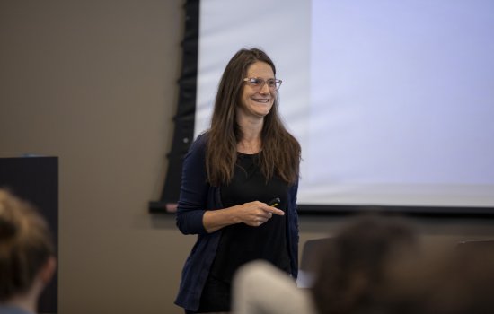 A woman speaks in front of a projector screen at the UAlbany mathematics conference.