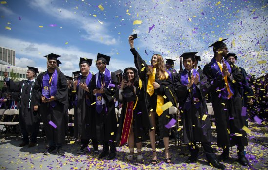 Purple and gold confetti surrounds new graduates at the UAlbany Entry Plaza lawn.